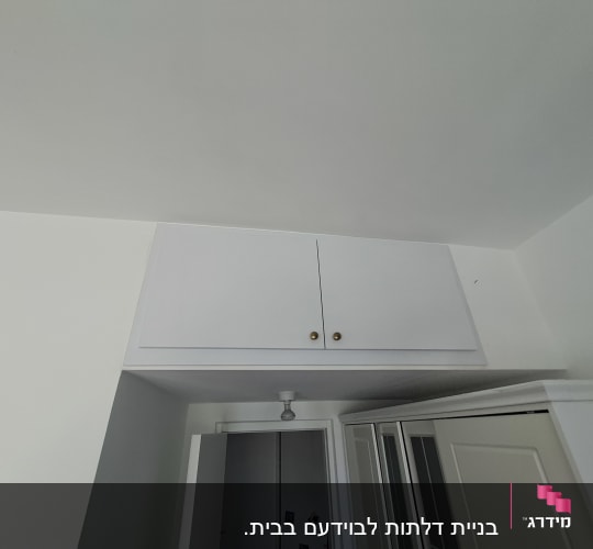 ארון קיר לבן עם דלתות וידיות זהב